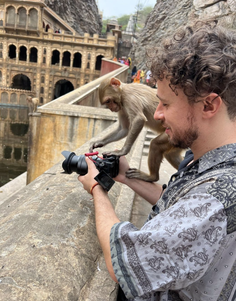 Fotografía de Luisito Comunica explorando una ciudad antigua con un mono. 